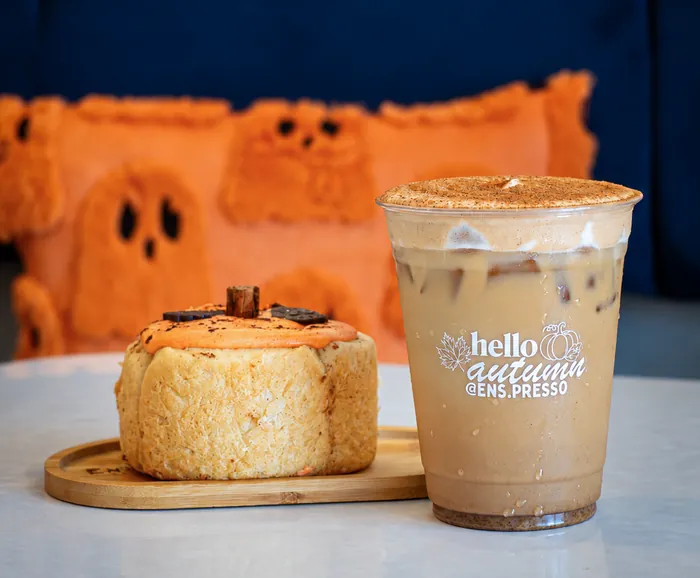 Rol decorado de calabaza junto a un latte de temporada helado